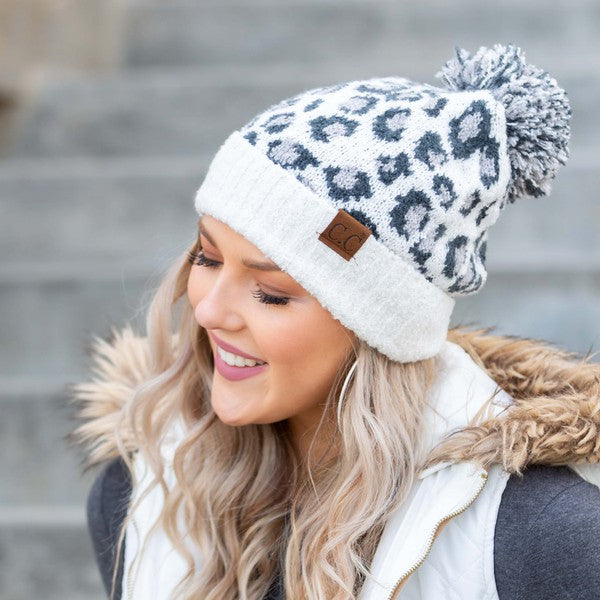 Woman wearing a leopard print beanie with a pom-pom on a blurred background
