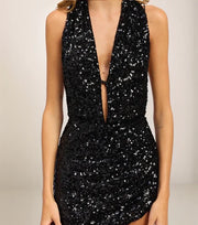 Black sequin dress with a plunging neckline on a neutral background
