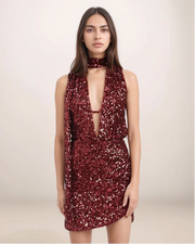 Woman wearing a red sequin dress against a plain background