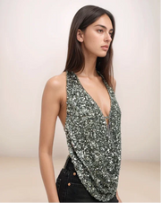 Woman wearing a sparkly green top against a plain background