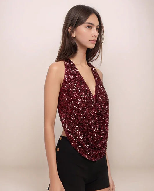 Woman wearing a sparkly red top and black shorts on a plain background