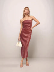 Woman wearing a strapless red dress against a plain background