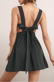 Black Maeve mini dress back view with open back, wide shoulder straps, tie-back detail, and elastic waist