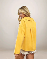 Woman wearing a yellow jacket with a plain background