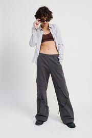 Person wearing a plaid shirt, brown top, and gray cargo pants on a white background