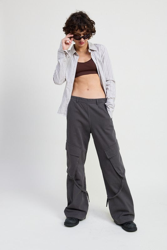 Person wearing a plaid shirt, brown top, and gray cargo pants on a white background