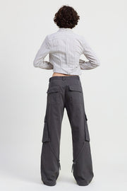 Person wearing gray cargo pants and a striped shirt on a white background