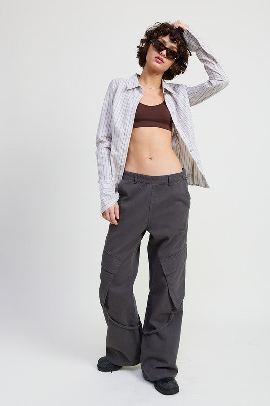 Person wearing a striped shirt, brown top, and gray cargo pants on a white background