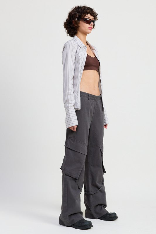 Person wearing a striped shirt, brown top, and gray cargo pants on a white background