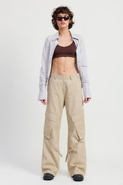 Woman wearing a plaid shirt, brown top, and beige cargo pants on a white background