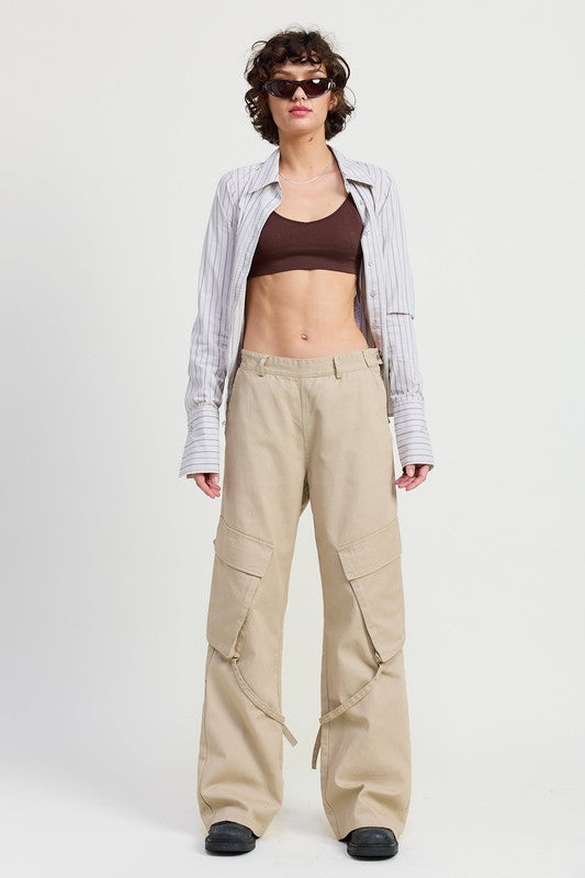 Woman wearing a plaid shirt, brown top, and beige cargo pants on a white background