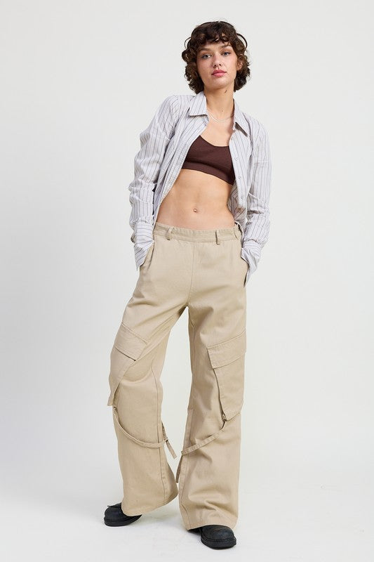 Woman wearing a plaid shirt, brown top, and beige cargo pants on a white background