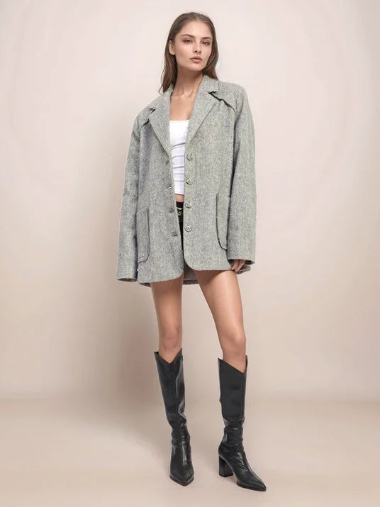 Woman wearing a gray coat and black knee-high boots on a beige background