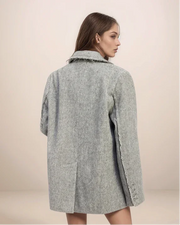 Woman wearing a gray coat against a beige background