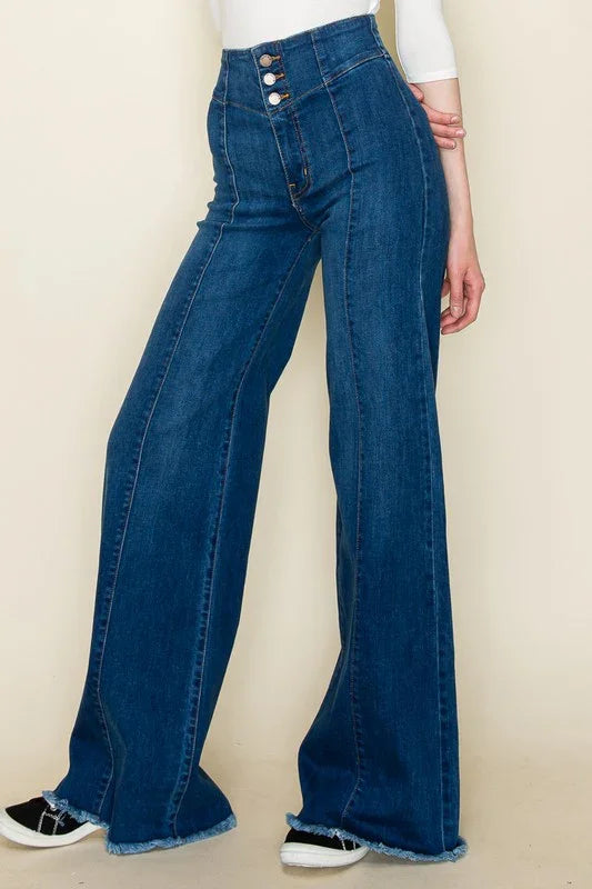 Medium wash flared jeans worn by a person on a beige background