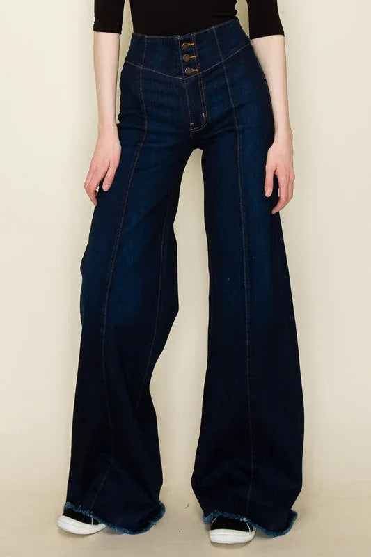 Person wearing high-waisted dark wash blue jeans on a beige background