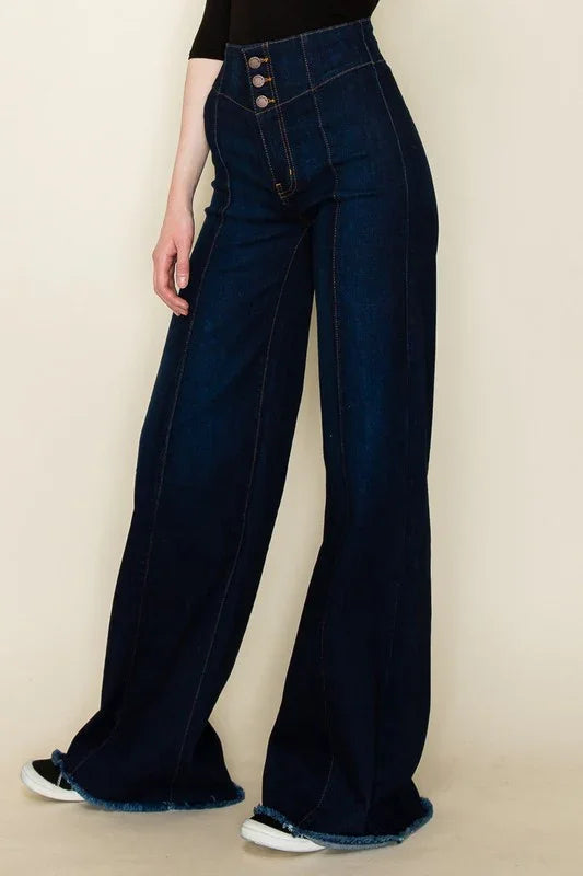 Dark  blue wide-leg jeans worn by a person on a beige background