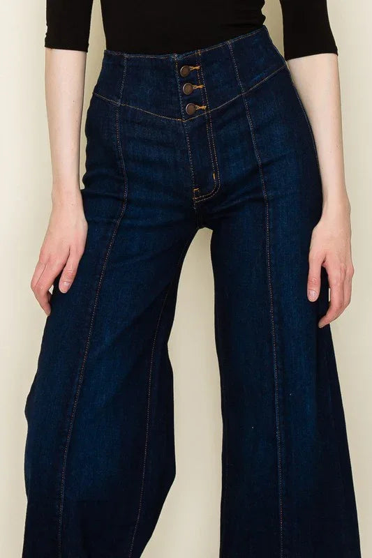 Person wearing dark blue wide-leg jeans against a plain background
