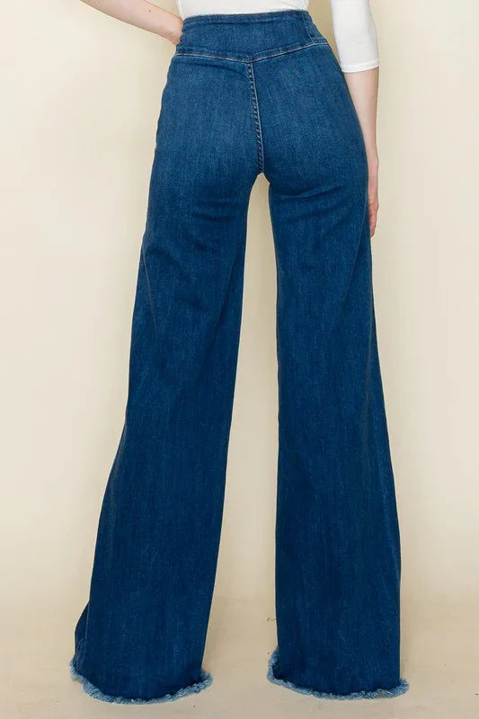 Blue denim wide-leg pants worn by a person on a beige background