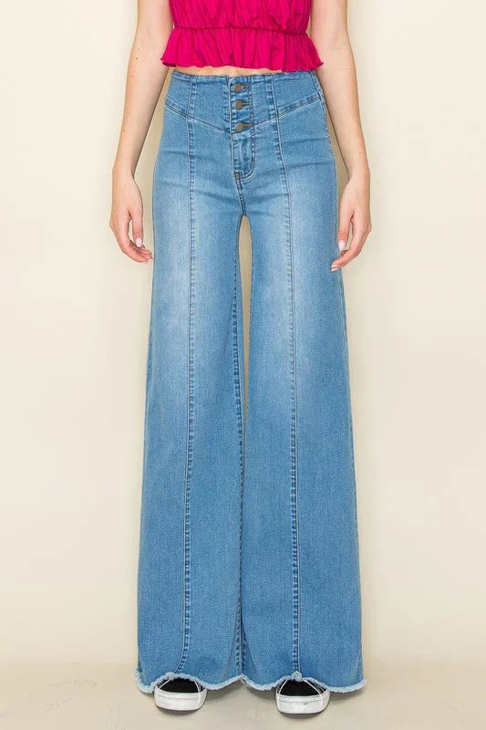 Person wearing high-waisted light wash blue jeans on a beige background