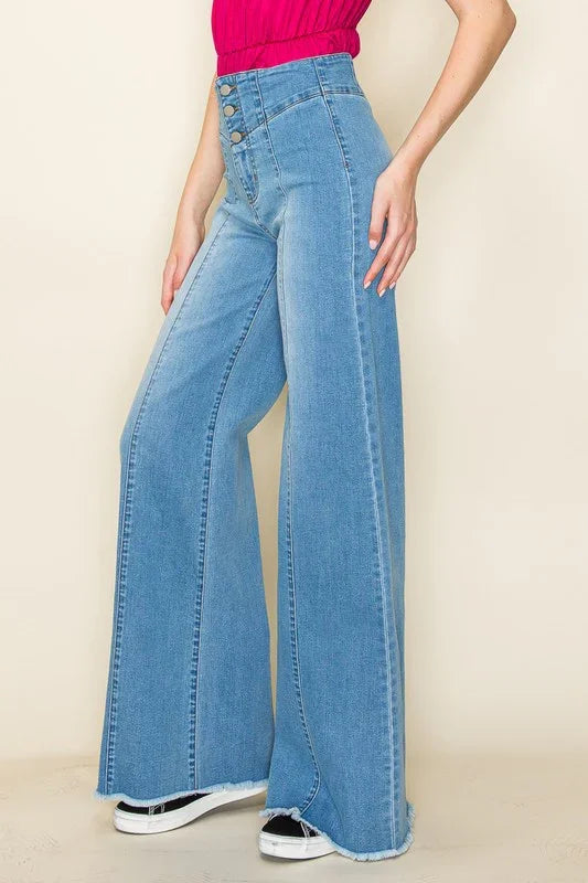Person wearing light blue flared jeans on a beige background