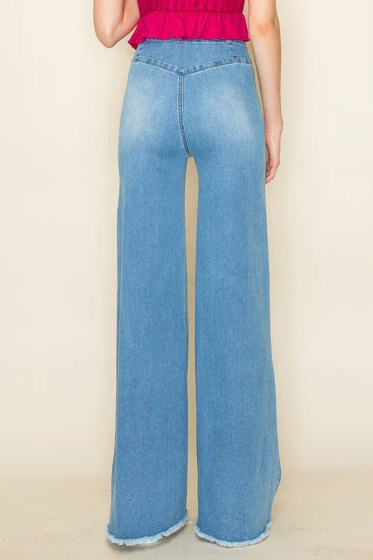 Light blue wide-leg jeans worn by a person on a beige background