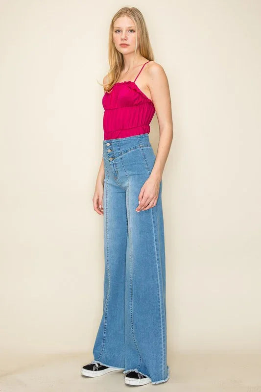 Woman wearing a pink top and blue jeans against a beige background