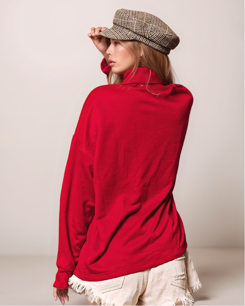 Person wearing a red sweater and plaid hat on a plain background