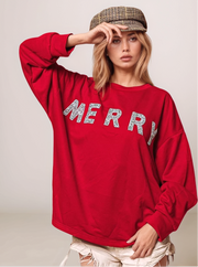 Person wearing a red sweatshirt with 'MERRY' text, posing against a plain background
