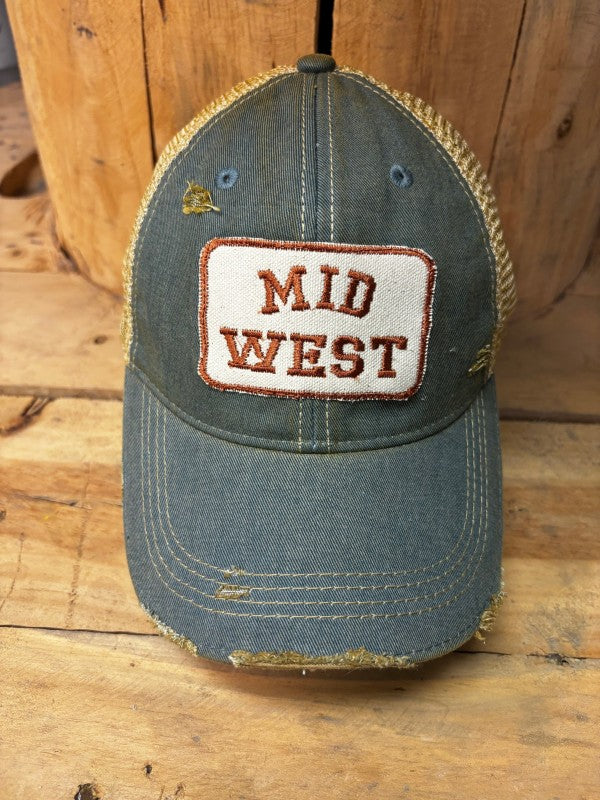Blue cap with 'Mid West' patch on a wooden surface