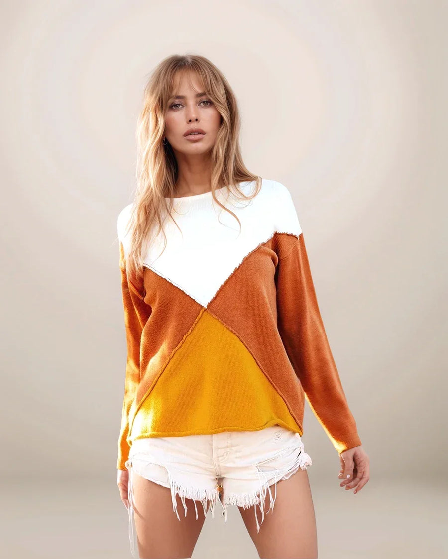 Woman wearing a color-blocked sweater with white, orange, and yellow sections on a plain background.
