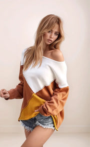 Woman wearing a color-blocked sweater with white, brown, and yellow sections on a plain background.
