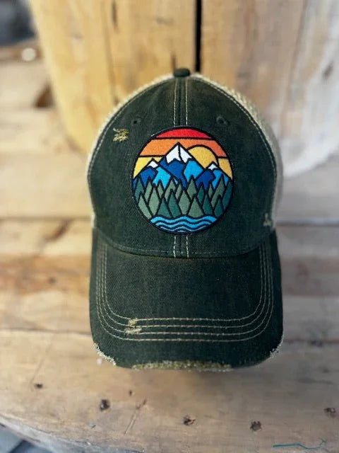 Green cap with a colorful mountain design on a wooden surface