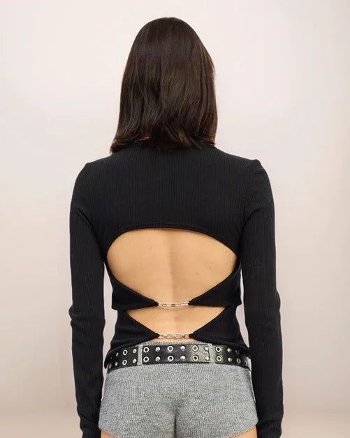 Person wearing a black long-sleeve top with cut-out design on the back, standing against a plain background.