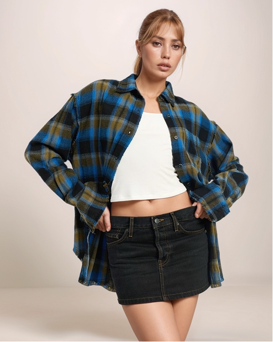 Woman wearing a plaid shirt over a white top and black denim skirt on a beige background