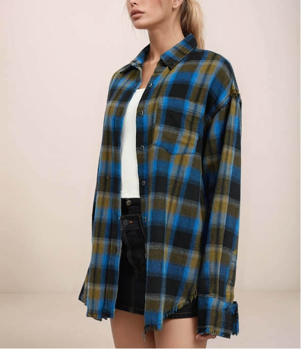 Person wearing a blue and green plaid shirt over a white top and black shorts on a beige background