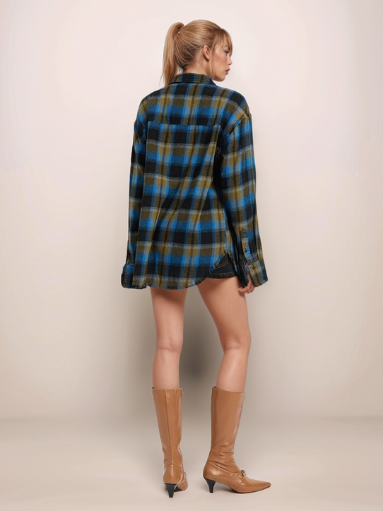 Person wearing a plaid shirt and brown boots on a plain background