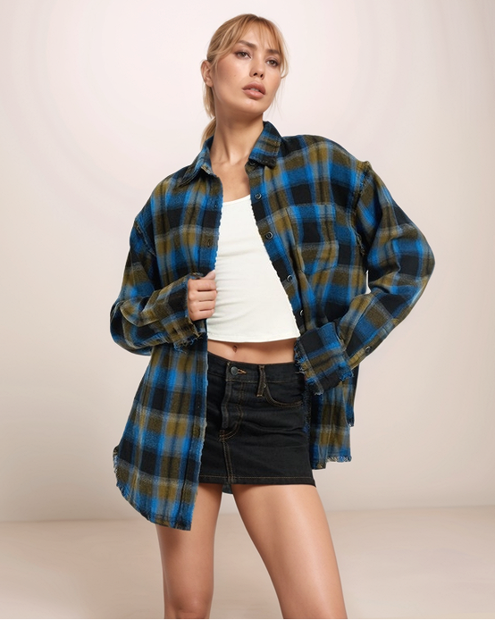 Woman wearing a blue and green plaid shirt over a white top and black shorts on a beige background