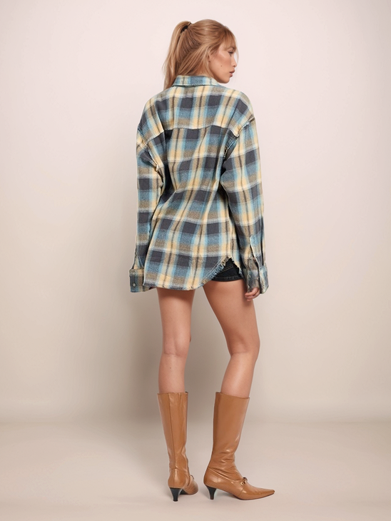 Woman wearing a plaid shirt and brown boots on a plain background