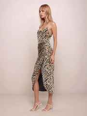 Woman wearing a strapless animal print dress with a slit on a plain background