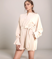 Woman wearing a beige romper with a plain background