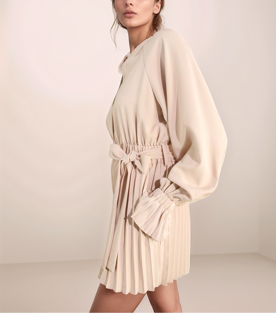 Woman wearing a beige dress with a belt against a plain background