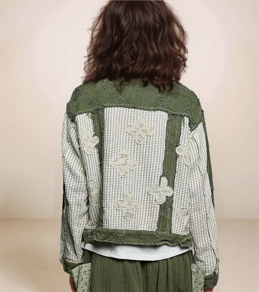 Person wearing a green textured jacket with floral patterns on a beige background