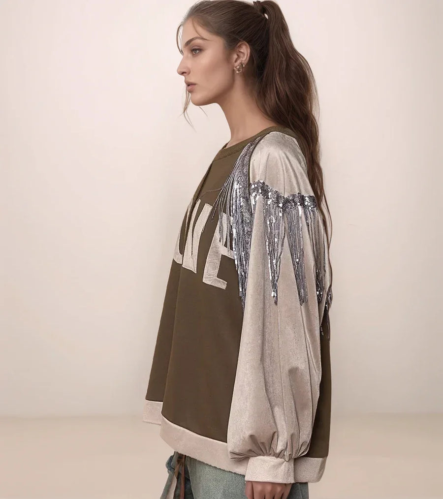 Woman wearing a green and beige layered outfit with sequin details on a plain background