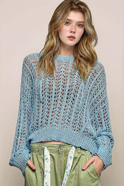 Front view of a model in a light blue POL openwork knit sweater with a round neck and long sleeves, paired with olive green utility pants.