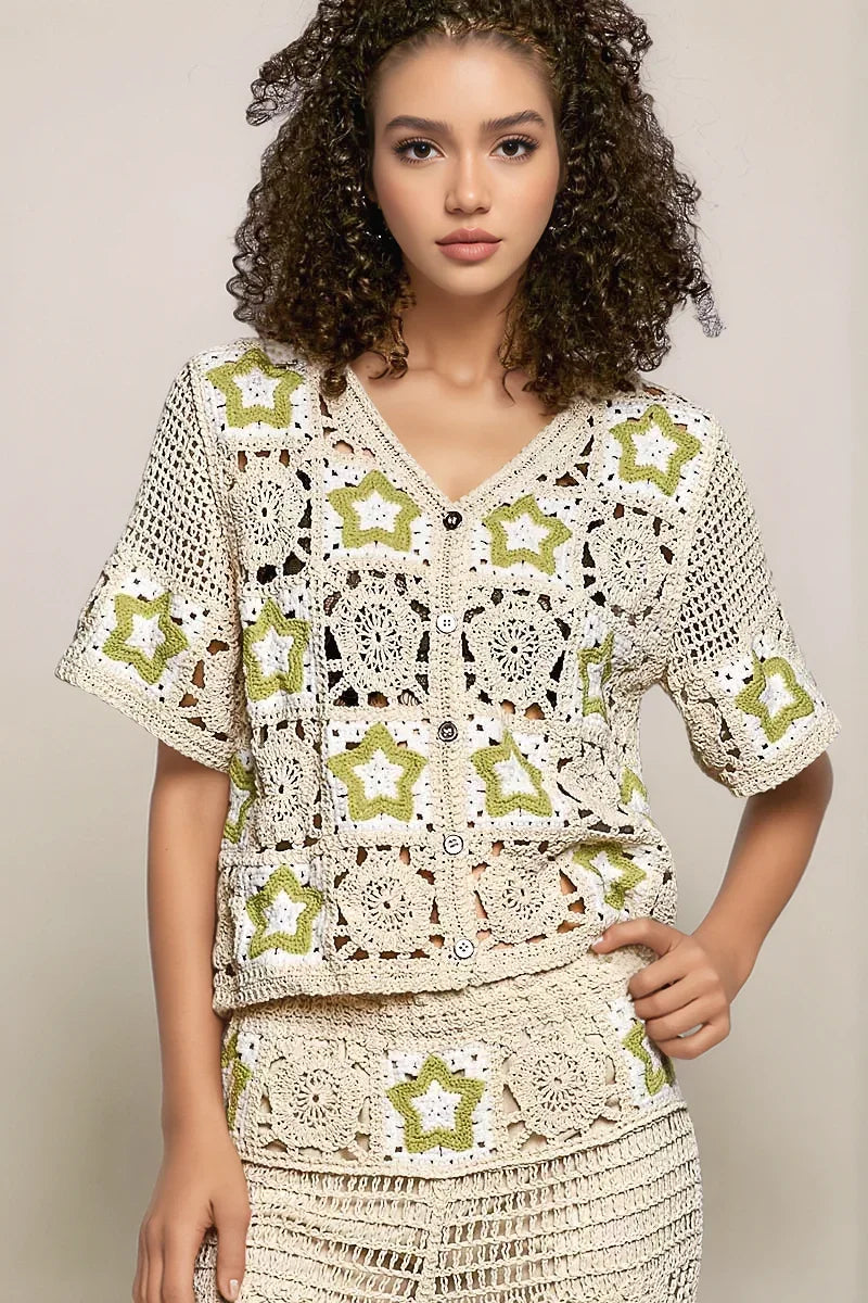 Front view of the cream POL Stardust Star Crochet Cardigan featuring a V-neck, functional buttons, and vibrant green star motifs integrated into the intricate openwork knit.