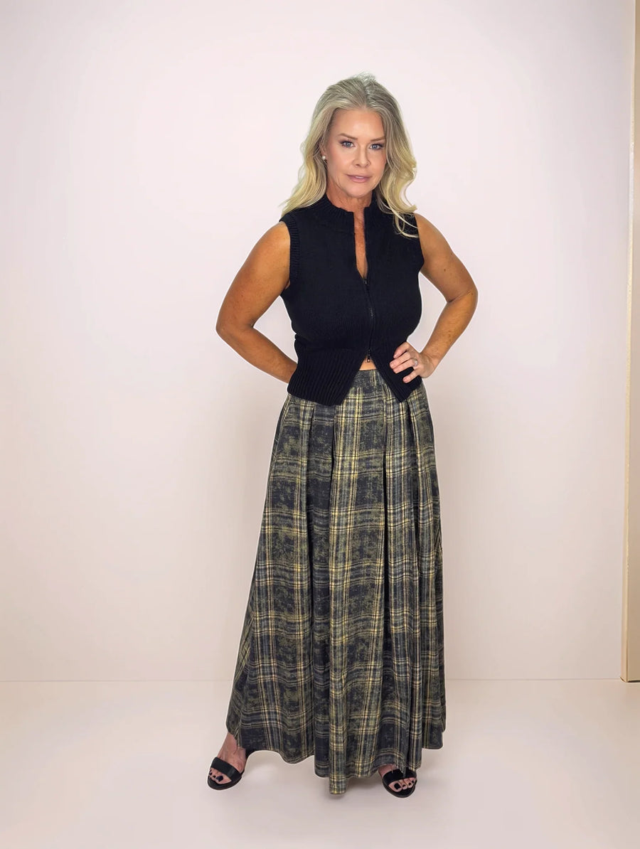 Woman wearing a black sleeveless top and plaid skirt on a white background