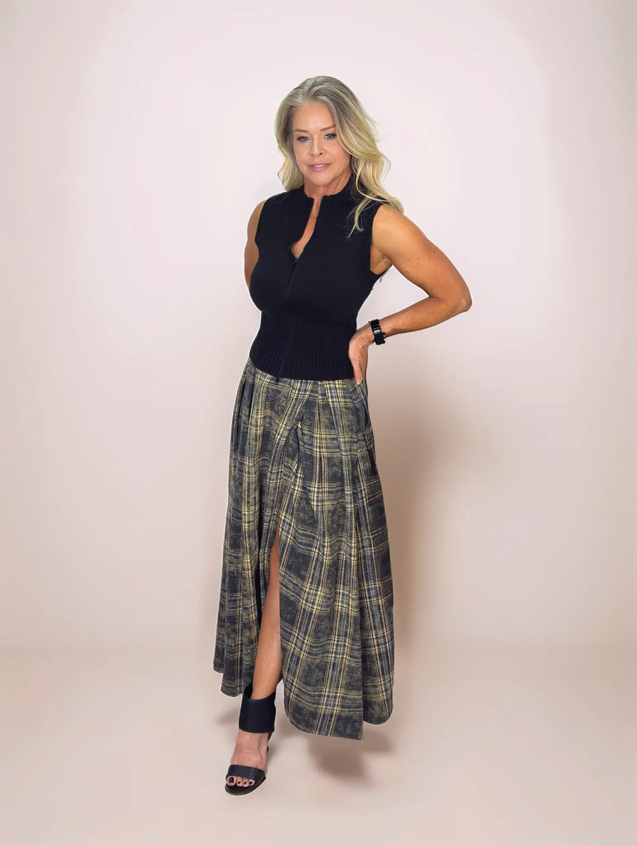 Woman wearing a black sleeveless top and plaid skirt on a plain background