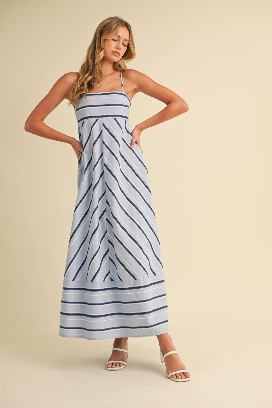 Woman wearing a blue and white striped dress on a beige background
