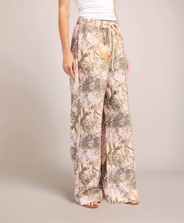 Person wearing camouflage-patterned wide-leg pants on a plain background